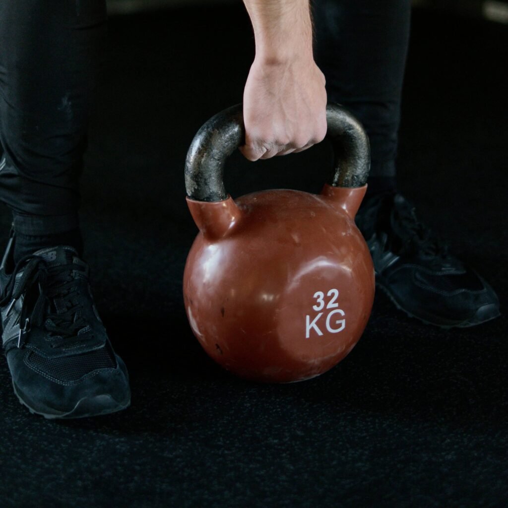  a person holding a 32 kg kettlebell, emphasizing strength  in training for advanced muscle hypertrophy techniques