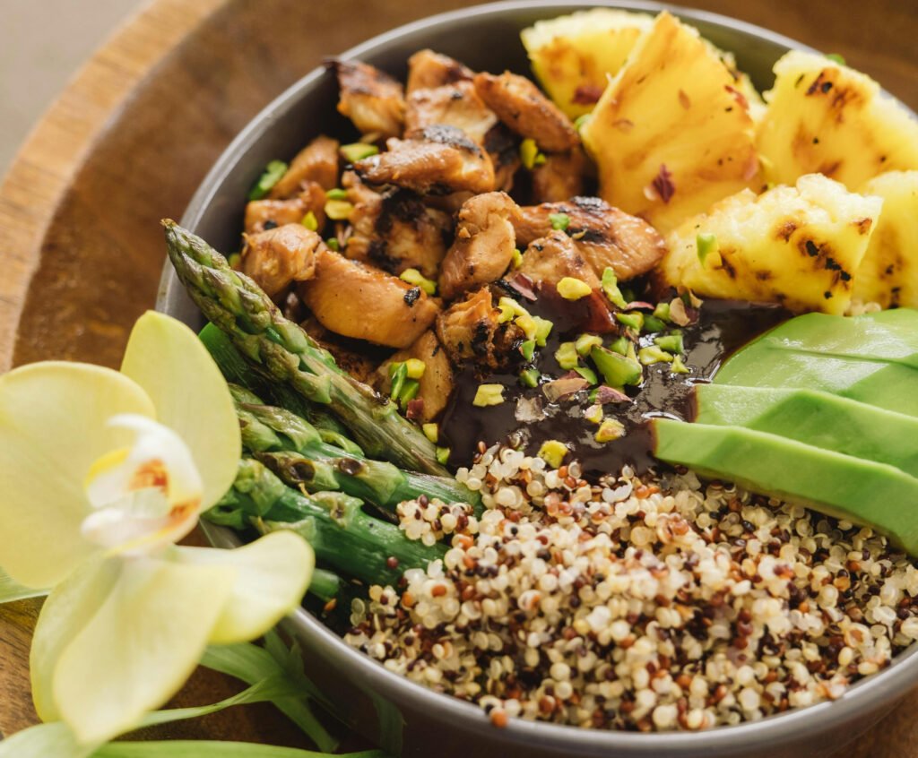 Grilled Chicken Salad with Avocado and Quinoa Grilled chicken salad with avocado, quinoa, and mixed greens on a brown plate