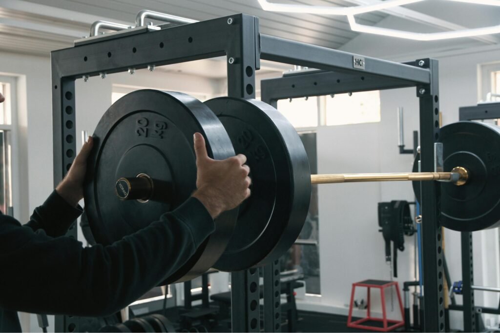 An athlete adding weight plates to a barbell before a strength training set