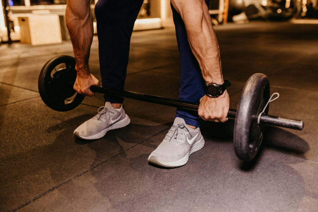 Man performing a barbell deadlift in a gym, focusing on strength training and lower body workout with free weights.