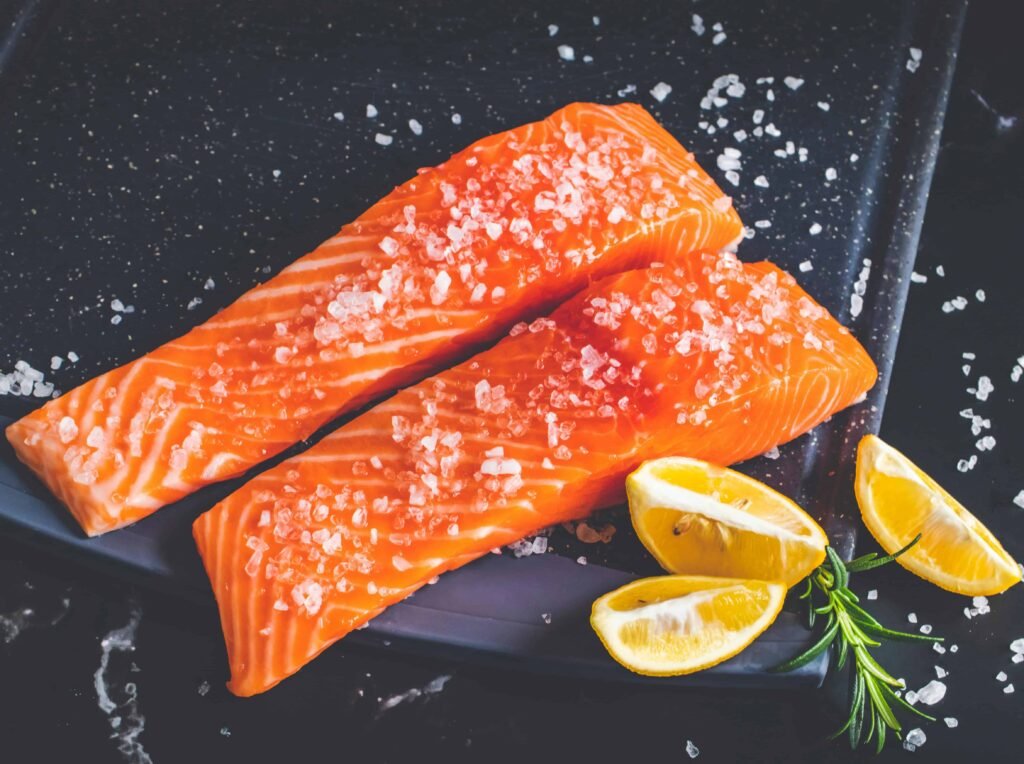 Salmon with lemon and salt on a black plate