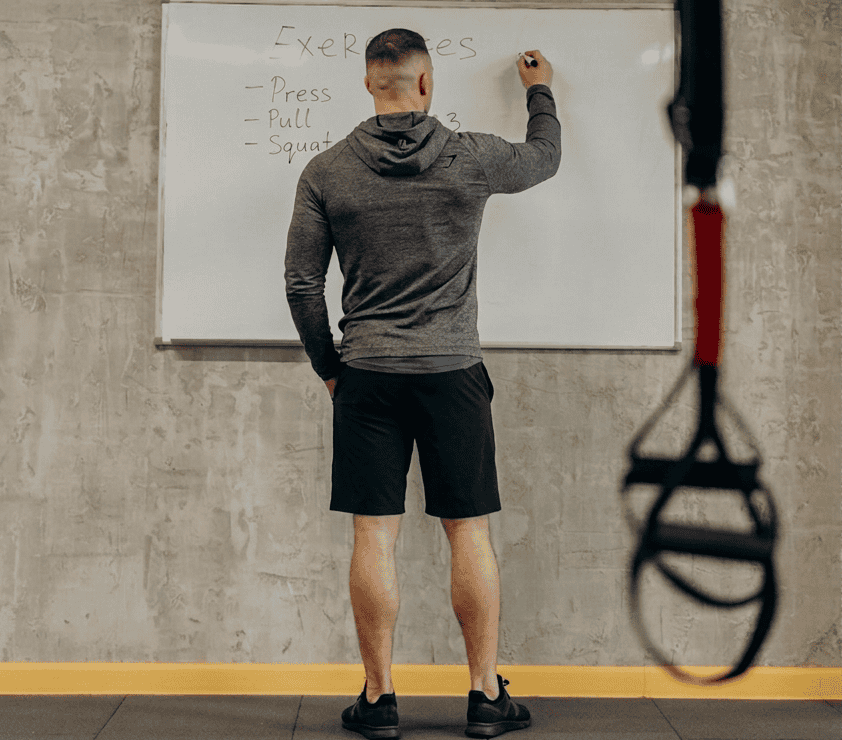 An athlete writing a workout plan on a gym blackboard