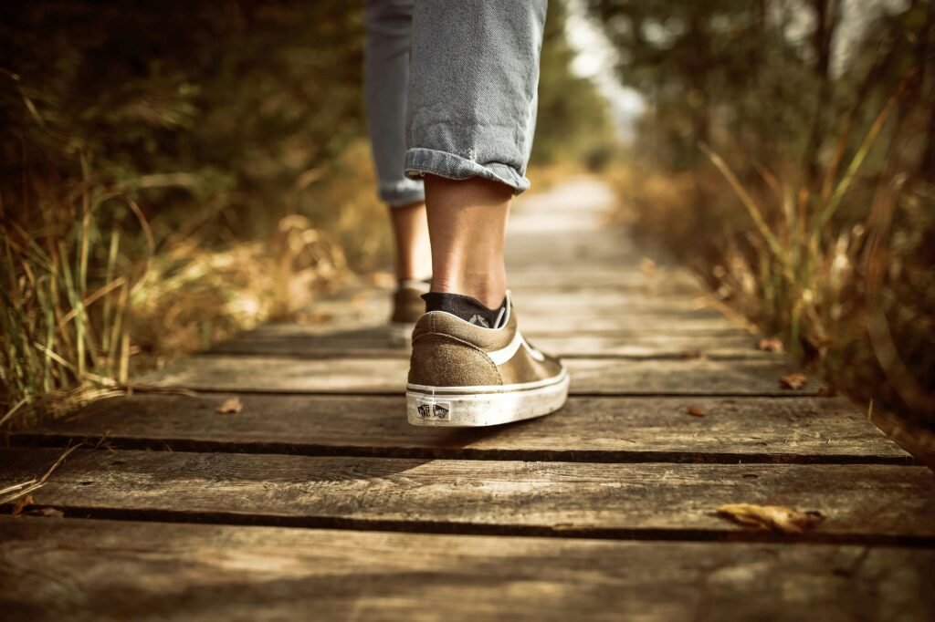 Close-up of a person walking on a wooden path outdoors in nature