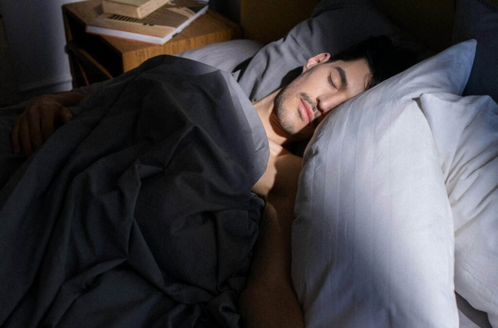 A person sleeping peacefully in bed with grey sheets, bathed in soft sunlight
